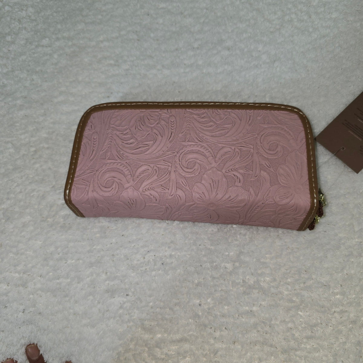 Pink wallet with embossed design on a textured surface