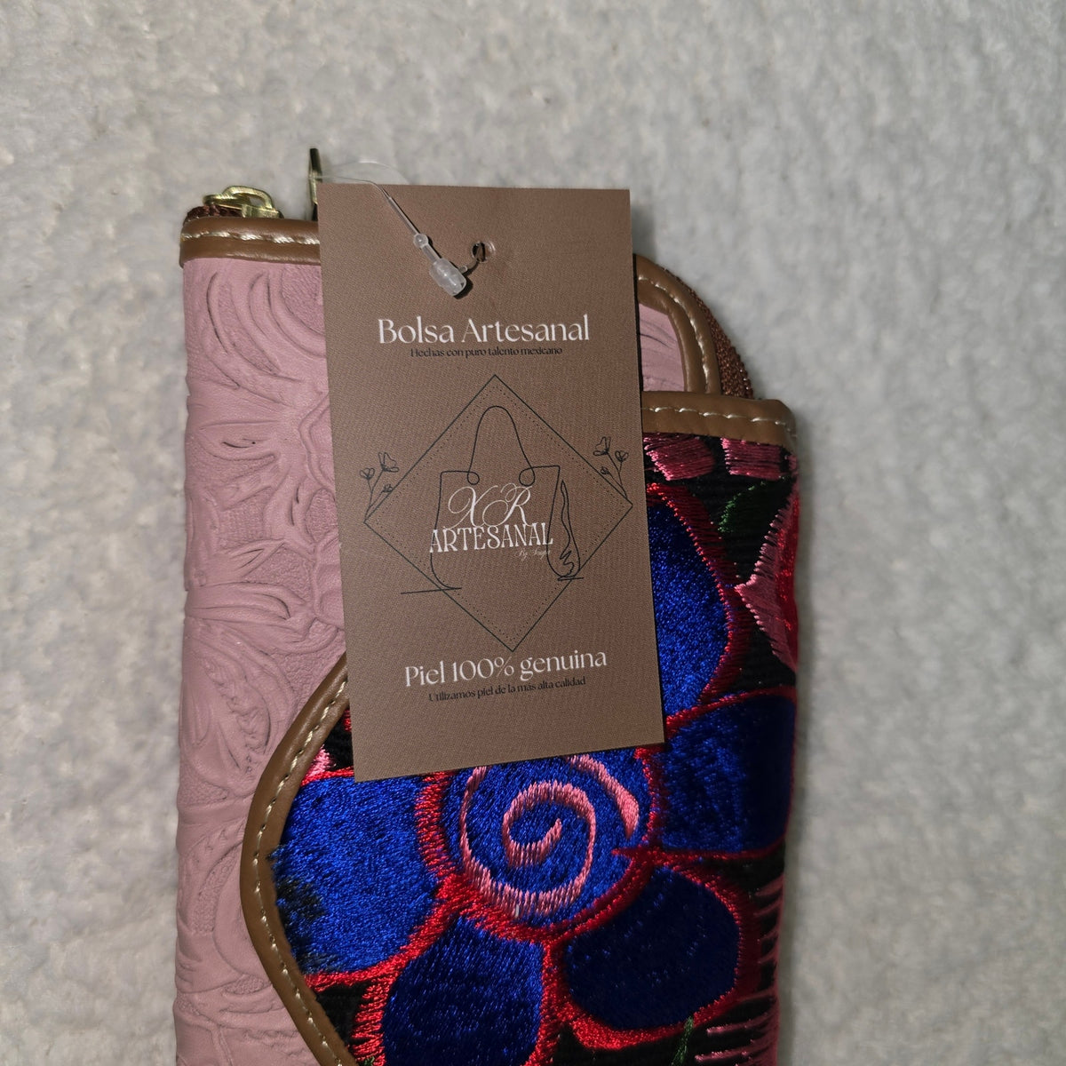 Handcrafted leather wallet with floral embroidery and a visible brand tag  