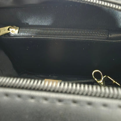 Close-up of a black handbag with gold zippers
