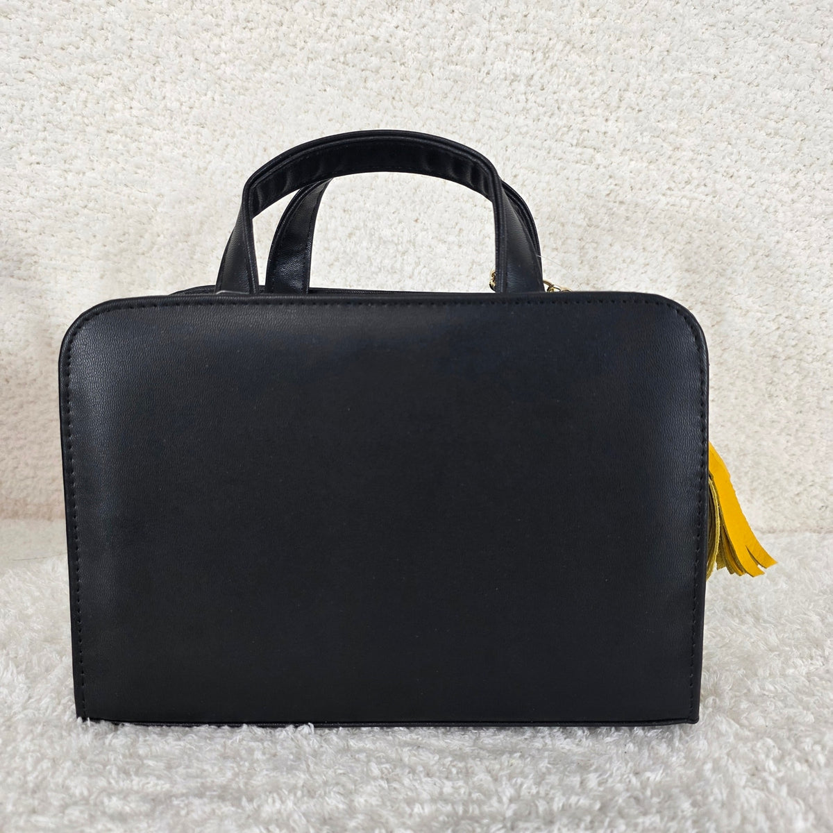 Black handbag with a yellow tassel 