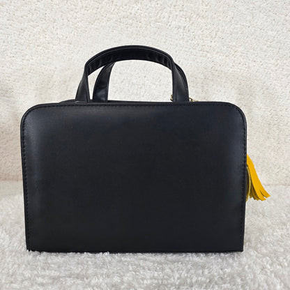 Black handbag with a yellow tassel 