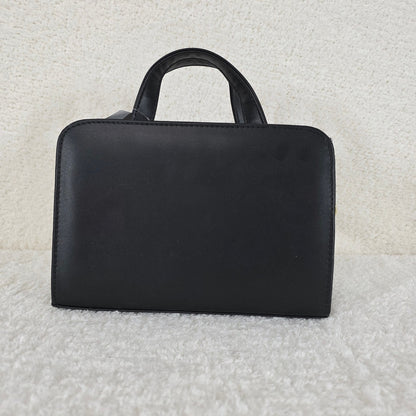 Black handbag on a textured light gray background